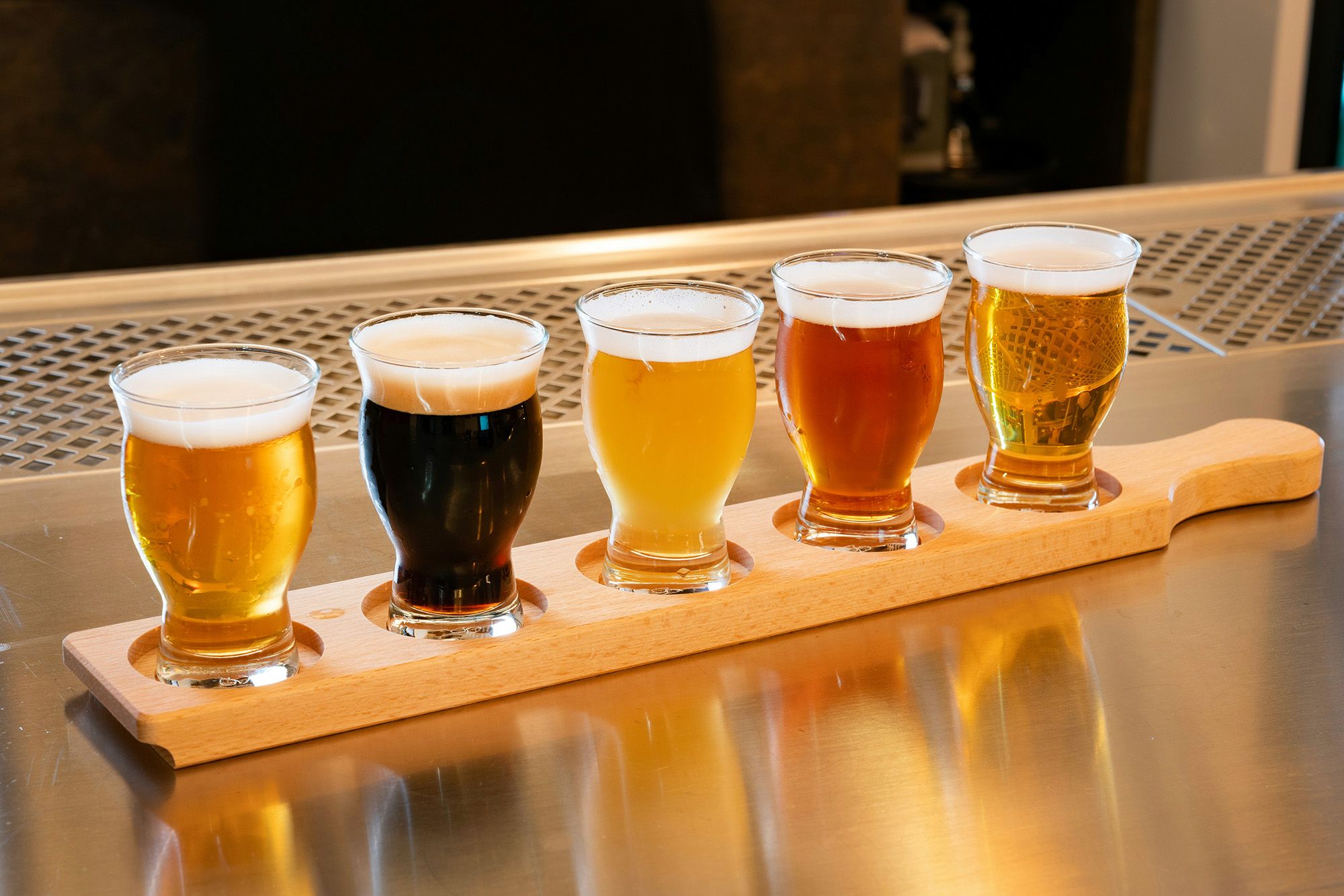 A tasting flight of five beers on a wooden paddle at a bar